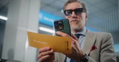 Havaalanı Terminali: Akıllı Telefon kullanarak, Bilgi Denetleyerek Başarılı Girişimci Uçak Tarayıcı Biletleri. VIP Ayrılış Salonunda Uçağı Bekleyen İşadamı. E-Bilet Teknolojisi. Görüntüyü Kapat.