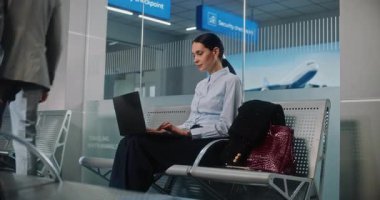 Havaalanı Terminali: Başarılı iş kadını Laptop kullanıyor, e-iş yapıyor ya da uzaktan çalışıyor, kameraya bakıyor. Girişimci iş seyahatine çıkıyor, Kalkış Salonunda Uçuşu Bekliyor. Doli Vuruşu.