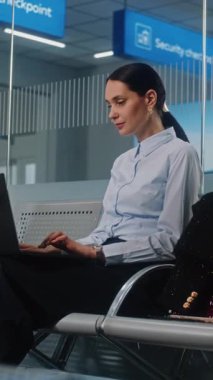 Havaalanı Terminali: Başarılı iş kadını Laptop kullanıyor, e-iş yapıyor ya da uzaktan çalışıyor, kameraya bakıyor. Girişimci iş seyahatine çıkıyor, Kalkış Salonunda Uçuşu Bekliyor. Dikey Çekim.