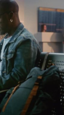 Kalabalık Uluslararası Havaalanı Terminali: Laptop kullanan Afrikalı Amerikalı Adam, Küçük Bebekle Oturan Kadın. Çeşitli Yolcular, Kalkış Salonunda Uçak Uçuşunu Bekleyen Yolcular. Dikey Çekim.