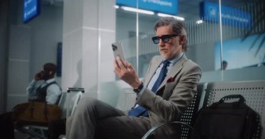 Havaalanı Terminali: Başarılı İşadamı Smartphone 'da İş Ortağıyla Konuşuyor, Video Call, Oturma Salonu. Girişimci Uçak Uçuşunu Bekliyor, Seyahate Çıkıyor. Yavaş Hareket.