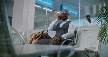 Uluslararası Havalimanı Terminali: Afrikalı Amerikalı İşadamı Cep telefonuyla İş Ortağıyla Konuşuyor. Başarılı Girişimci, Hava Yolları Merkezinin Kalkış Salonunda Uçuş Bekliyor, Seyahate Çıkıyor.