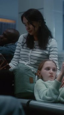 Gece Yatılı Salon 'da Anne ve Kızı: Koltuklarda yatan yorgun genç kız, Akıllı Telefon kullanan kadın. Uluslararası Havaalanı Terminali 'nde rötarlı uçuş bekleyen çeşitli yolcular. Dikey Çekim.