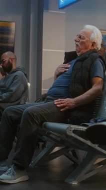 Kalabalık Uluslararası Havalimanı Terminali: Yaşlı Adam Kalp krizi geçiriyor, Ayrılış Salonunda Sandığı Tutuyor. Çeşitli İnsanlar Yaşlı Yolculara Yardım Ediyor, Tıbbi Yardım Çağırıyor. Dikey Çekim.