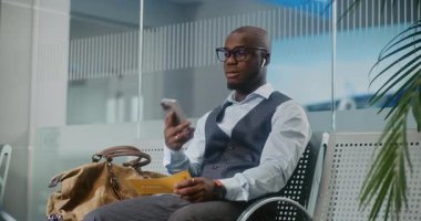 Havaalanı Terminali: Afrikalı Amerikalı Girişimci Gecikmeli Uçuş Tutma Uçak Bileti Hakkında Rahatsız Oldu, Telefonda Konuşuyor. İş adamı, Ayrılış Salonu 'nda oturuyor, iş gezisine çıkıyor. Doli Vuruşu.