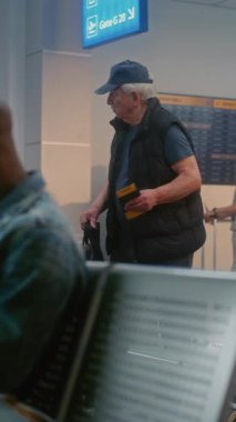 Kalabalık Uluslararası Havaalanı Terminali: Afro-Amerikan Genç Adam Oturuyor, Uçak Uçuşunu Bekliyor, Seyahate Çıkıyor. Ayrılış Salonunda çok ırklı insanlar ve yolcular var. Dikey Çekim.