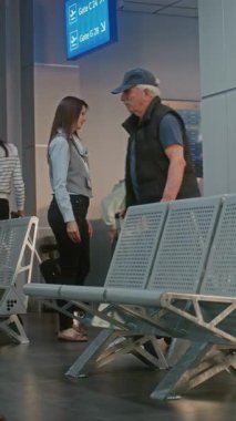 Kalabalık Uluslararası Havalimanı Terminali 'ndeki Çeşitli İnsanlar: Bavulu, Belgeleri ve Pasaport Kontrolünden Sonra Kalkış Salonunda Oturan Yaşlı Adam, Uçuşu Bekliyor. Dikey Çekim.