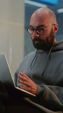 Kalabalık Uluslararası Havaalanı Terminali: Laptop 'ta Uzaktan Çalışan Adam, Çevrimiçi Görüntü Aranıyor, Uçak Bekliyor. Yatılı Salon 'da Dijital Gadget kullanan çeşitli yolcular. Dikey Çekim.