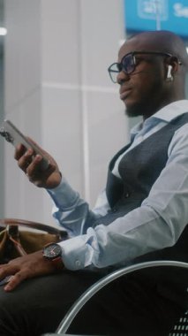 Havaalanı Terminali: Başarılı Girişimci Telefonu Kullanıyor, E-posta Gönderiliyor. Afrika kökenli Amerikalı iş adamı, kalkış salonunda uçak bekliyor, iş gezisine çıkıyor. El bilgisayarı. Dikey Çekim.