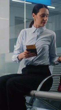 Uluslararası Havalimanı Terminali: Çanta ve Belgelerle Başarılı İşkadını Telefonu Kullanıyor, Kalkış Salonunda Uçak Uçuşunu Bekliyor. Kadın Girişimci İş Gezisine Gidiyor. Dikey Çekim.