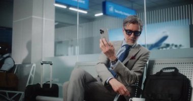 Havaalanı Terminali: Başarılı Girişimci Akıllı Telefondan Yatırımcıyla Konuşuyor, Video Sohbet, Kahve İçme. İş adamı kalkış salonunda uçuşu bekliyor, iş gezisine çıkıyor. Yavaş Hareket.