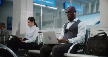 Uluslararası Havalimanı Terminali 'ndeki VIP Gidiş Salonu: Laptop' ta iş yapan Afrikalı Amerikalı İş Adamı. Uçuşu Bekleyen Dijital Gadget 'larla çalışan çok ırklı iş adamları. Doli Vuruşu.