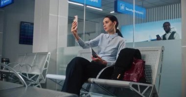 Havaalanı Terminali: Akıllı Telefondan Yatırımcıyla Konuşan Kadın Girişimci, Video Sohbeti. Başarılı bir iş kadını kalkış salonunda uçak bileti bekliyor, iş seyahatine çıkıyor. Doli Vuruşu.