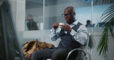 Uluslararası Havalimanı Terminali: Afro-Amerikalı İşadamı Ayrılış Salonunda Oturuyor, Kahve İçiyor. Başarılı Girişimci Uçuşu Bekliyor, İş Gezisine Çıkıyor. Yavaş Hareket, Orta Çekim.