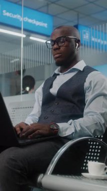 Havaalanı Terminali: Laptop kullanan, kahve içen, e-iş yapan Afrikalı Amerikalı Girişimci. İş adamı Uzaktan Çalışmalar Kalkış Salonunda Uçuşunu Bekliyor, İş Gezisine Gidiyor. Dikey Çekim