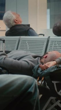 Kalabalık Uluslararası Havaalanı Terminali: Yatılı Salondaki Koltuklarda Uyuyan Yorgun Adam. Çeşitli İnsanlar ve Yolcular Gecikmeli Uçuşu Bekliyor. Turizm ve Seyahat. Dikey Çekim