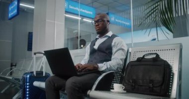 Havaalanı Terminali: Laptop kullanan ve kahve içen Afrikalı Amerikalı Girişimci, e-ticaret yapıyor. İş adamı Uzaktan Çalışmalar Kalkış Salonunda Uçuşunu Bekliyor, İş Gezisine Gidiyor. Doli Vuruşu.