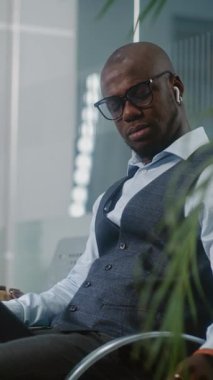 Havaalanı Terminali: Başarılı Girişimci Dijital Tablet Kullanıyor, Kahve İçiyor. Afrika kökenli Amerikalı iş adamı, kalkış salonunda uçak bekliyor, iş gezisine çıkıyor. Yavaş Hareket, Dikey Çekim