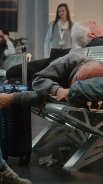 Kalabalık Uluslararası Havaalanı Terminali: Yatılı Salondaki Koltuklarda Uyuyan Yorgun Adam. Çeşitli İnsanlar ve Yolcular Gecikmeli Uçuşu Bekliyor. Turizm ve Seyahat. Dikey Çekim