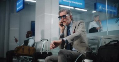 Uluslararası Havalimanı Terminali: Başarılı Adam İptal Edilen ya da Gecikmeli Uçuş Hakkında Sinirleniyor, Telefonda Konuşuyor. Ciddi İşadamı Ayrılış Salonu 'nda oturuyor, iş gezisine çıkıyor. Yavaş Hareket.