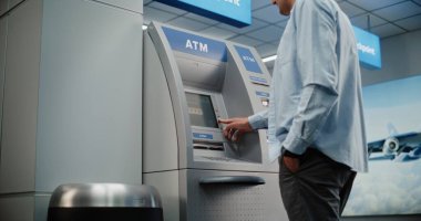 Kalabalık Havalimanı Terminali 'ndeki Cash Machine: ATM' nin tuşlarına basan adam, şifre girişi, para çekme, para çekme. Otomatik veznedar makinesi, bankacılık hizmetleri, işlemler. Orta Çekim.