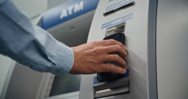 Modern Cash Machine: Bilinmeyen Adam, NFC Reader for Contacless Cash Retdrawal Traaction 'a Akıllı Telefon Koyuyor, ATM' ye PIN kodunu giriyor. Bankacılık, Finansal Operasyonlar. Kapat.
