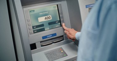 Cash Machine: Tanınmayan Adam Klavyeden PIN kodunu giriyor, Para çekme operasyonunu seçiyor, Miktar 'a giriyor ve ATM' den Amerikan Doları alıyor. Bankacılık ve İşlemler. Kapat..