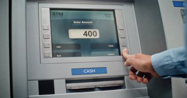 Cash Machine: Tanınmayan Adam Klavyeden PIN kodunu giriyor, Para çekme operasyonunu seçiyor, Miktar 'a giriyor ve ATM' den Amerikan Doları alıyor. Bankacılık ve İşlemler. Kapat..