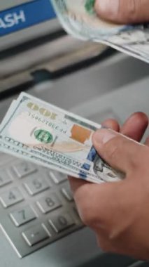 Tanınmayan Adam, İşadamı ATM 'den para çektikten sonra Amerikan Doları' nı Ellerinde Sayıyor. Bankacılık, para çekme, finansal operasyonlar. Dikey Çekim.