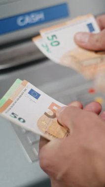 Bankamatikten nakit para çektikten sonra Euro Faturalarını Sayan Tanınmayan Adam 'ın Kapanışı. Bankacılık, para çekme, finansal operasyonlar. Dikey Çekim.