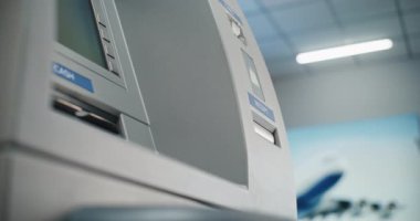 Havalimanı Terminalinde Para Makinesi: Bilinmeyen Kişi Akıllı Telefonu Temassız Para Çekme İşlemi için NFC Okuyucusuna Koyuyor, ATM 'deki Düğmelere Basıyor. Banka hizmetleri. Görüntüyü Kapat.