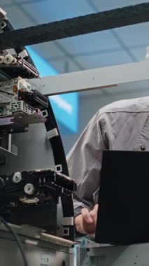 Havalimanı Terminali 'ndeki ATM Umumi Nakit Dispenser Machine' de teknisyen. Erkek İşçi Dizüstü bilgisayar kullanarak ATM 'yi ayarlıyor. Bankacılık, nakit para çekme sistemleri ve ATM Tamiri. Dikey Çekim.