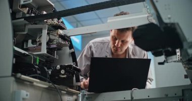 Modern Havalimanı Terminali 'ndeki Üniformalı Nakit Dispenser Machine' de ATM teknisyeni. Erkek İşçi Dizüstü bilgisayar kullanarak ATM 'yi ayarlıyor. Bankacılık Teknolojisi, Para çekme Sistemleri ve ATM Tamiri