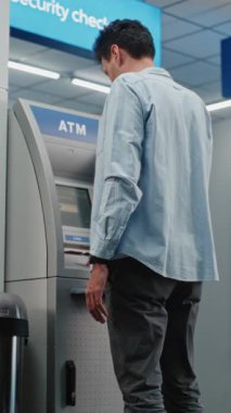 Havalimanı Terminali 'ndeki ATM Makinesi: ATM Klavyesindeki Düğmelere Basan Adam, Para Çekme Operasyonu için Şifre Girme, Nakit Alma. Para makinesi, banka hizmetleri ve işlemler. Dikey Çekim.
