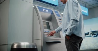Kalabalık Havalimanı Terminali 'ndeki Cash Machine: ATM' nin tuşlarına basan adam, şifre girişi, para çekme, para çekme. Otomatik veznedar makinesi, bankacılık hizmetleri, işlemler. Orta Çekim.