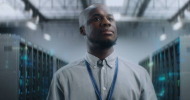 Afrikalı Amerikalı Yönetici, VFX ile Geleceğin Büyük Veri Merkezi 'nde Yürüyor, Gülümsüyor, Kameraya Bakıyor. Sunuculardaki İnternet Trafiğinin Animasyon Diyagramları. Bilgi Teknolojisi ve Dijitalleştirme.