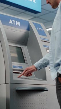 Kalabalık Havalimanı Terminali 'ndeki Cash Machine: ATM' nin tuşlarına basan adam, şifre girişi, para çekme, para çekme. Otomatik veznedar makinesi, bankacılık hizmetleri, işlemler. Dikey Çekim