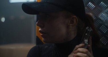 Siyah Taktik Ekipmanlı Kadın Gizli Ajanın Kapanışı ve Kaptanın Arkasında Bir Tabanca Saklanıyor. Memur Karanlık Ofis Binası 'nda suçluya saldırmaya ya da tutuklamaya hazırlanıyor. Epic Action Film Sahnesi.