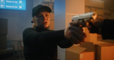 Action Movie Scene: Siyah Taktik Giyimli Kadın Polis Memuru ve Depoda Kaptan Yürüyor, Silah Tutuyor, Tabancalı Bilinmeyen Suçluyu Buluyor. Karanlık Bina 'da Saldırgan Ajan