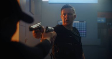 Gergin Savaş Filmi: İki Tehlikeli Suçlu Taktiksel Silahları Birbirine doğrultup Konuşuyor. Karanlık Ofis Binası 'nda Ajan Saldırgan Katil. Silahlı Çatışma Dramatik Sahnesi.