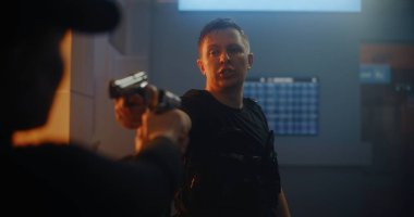 Silahlı Karşılaşma: Taktik Ekipmandaki İki Kızgın Suçlu Birbirlerine Silahlar Nişan Aldılar ve Konuşuyorlar. Karanlık Bina 'da Gangster Saldırısı. Epic Action Movie 'den Gergin ve Dramatik Sahne.