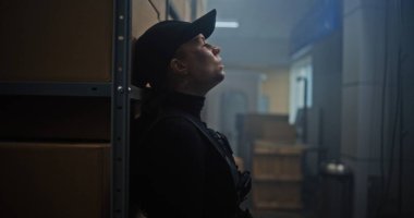 Siyah Taktik Ekipman 'daki Kadın Gizli Ajan ve Depo' da Saklanan Kaptan, Silah Tutan, Katille Konuşan. Memur Karanlık Depo Tesisinde Suçlu 'ya saldırmaya ya da tutuklamaya hazırlanıyor. Eylem Filmi Sahnesi