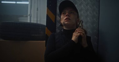 Siyah Taktik Ekipman 'daki Kadın Gizli Ajan ve Depo' da Saklanan Kaptan, Silah Tutan, Katille Konuşan. Memur Karanlık Depo Tesisinde Suçlu 'ya saldırmaya ya da tutuklamaya hazırlanıyor. Eylem Filmi Sahnesi