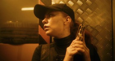 Siyah Taktik Ekipmanlı Kadın Gizli Ajanın Kapağı Arkasında Saklanıyor, Elinde Bir Tabanca Tutuyor. Memur Karanlık Ofis Binası 'nda suçluya saldırmaya ya da tutuklamaya hazırlanıyor. Epic Action Film Scene. Sıcak. Bak.