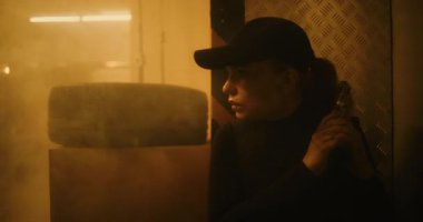 Action Movie Scene: Taktik Giyinen Kadın Polis Memuru ve Depo 'da Kaptan Saklanıyor, Silah Tutuyor, Suçluyla Konuşuyor. Ajan Karanlık Bina 'da Saldırıya Geçmek İçin Zaman Bekliyor. Sıcak. Bak..