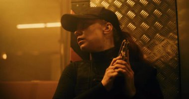 Aksiyon Filmi: Siyah Taktik Giysili Kadın Polis Memuru, Duvarın Arkasında Saklanıyor, Elinde Silah Tutuyor. Ajan Karanlık Ofis Binasında Saldırmak için Doğru Zaman Bekliyor. Yakın çekim. Sıcak. Bak..