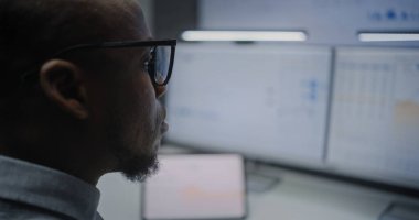 Çevrimiçi Ticaret Yazılımlı Çoklu Monitör Masaüstü Sistemi ile bilgisayar. Gerçek zamanlı borsa analizi, borsa grafikleri, borsa analizi. Ofiste çalışan Afro-Amerikan Yatırım Ajanı.