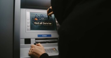 Kapüşonlu Vandal Graffiti İşaretleyici Kalemle ATM ekranını işaretliyor. Mülkiyete zarar verme, hizmet dışı ATM 'ye yasadışı grafitiyle zarar verme. Kamu Alanında Vandalizm.