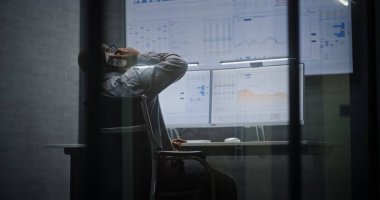 Finansal Analizci Telefonda Konuşuyor, Bilgisayar üzerinde Multi-Monitor Çalışma İstasyonu ile çalışıyor, Gerçek zamanlı borsa ve borsa grafiklerini analiz ediyor. Afrikalı Amerikalı İşadamı Geceleri Ofiste Çalışıyor.