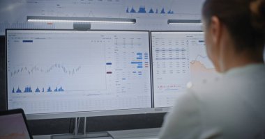 Multi-Monitor Workstation, Real-Time Stocks ve Exchange Market Charts ile bilgisayar üzerinde çalışan kadın finans analisti. Başarılı İşkadını Yatırım Bankası Ofisinde Gece Çalışıyor.